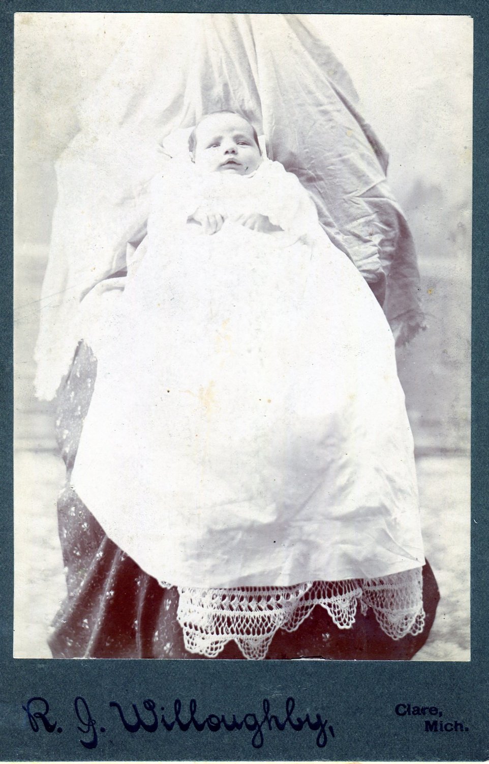 This ‘hidden mother’ photo was taken in Clare by photographer Robert Willoughby. Willoughby operated a studio in Clare from 1898-1904. The child is not identified.

Photos like this are commonly called ‘Hidden mothers’ as mothers stayed covered while holding their child still for long exposure times for early cameras.

Willoughby sold cabinet cards like this for 12 for $1.50.